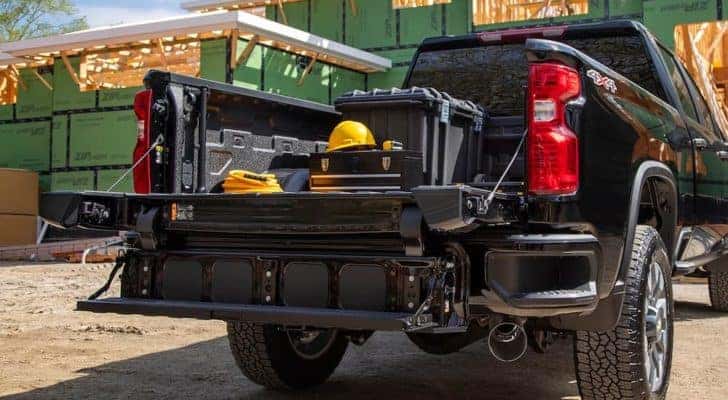 A black 2022 Chevy Silverado 2500 HD is shown from the rear with construction supplies in the bed.