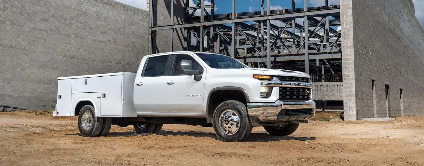 A white 2022 Chevy Silverado 3500HD Chassis Cab is shown parked at a construction site.