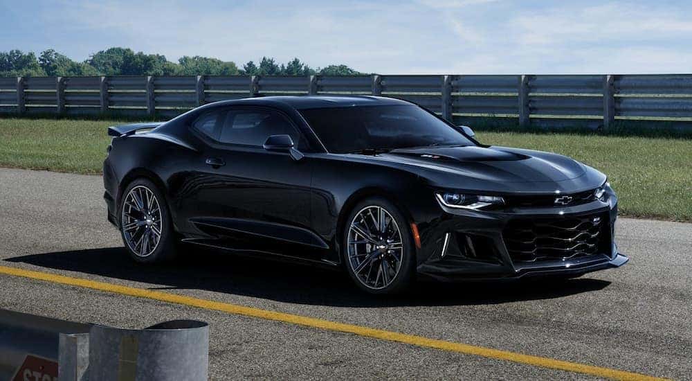 A black 2020 Chevy Camaro is shown from the side parked on a racetrack.