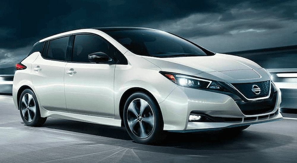 A white 2019 Nissan Leaf is shown driving on an open highway.