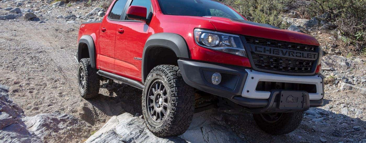 A red 2019 Chevy Colorado ZR2 is shown off-roading on a rocky trail.