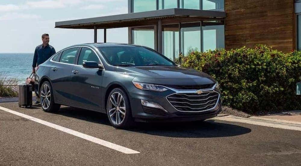 A grey 2020 Chevy Malibu is shown parked near a body of water.