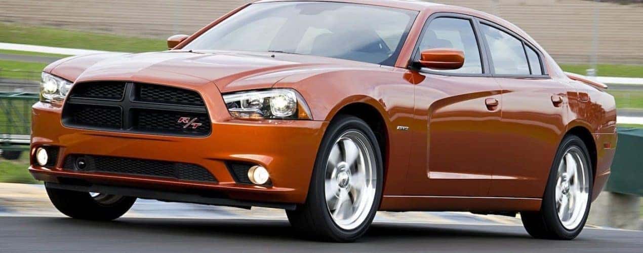 An orange 2011 used Dodge Charger is shown parked outside.