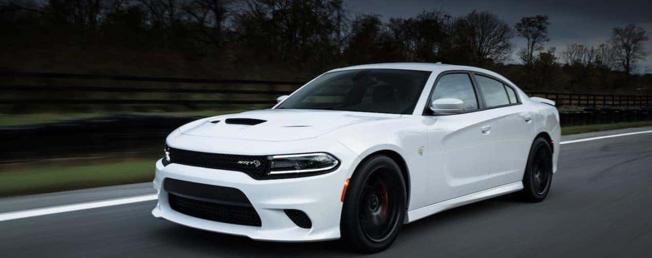 A white 2018 Dodge Charger SRT Hellcat is shown driving on an open road.