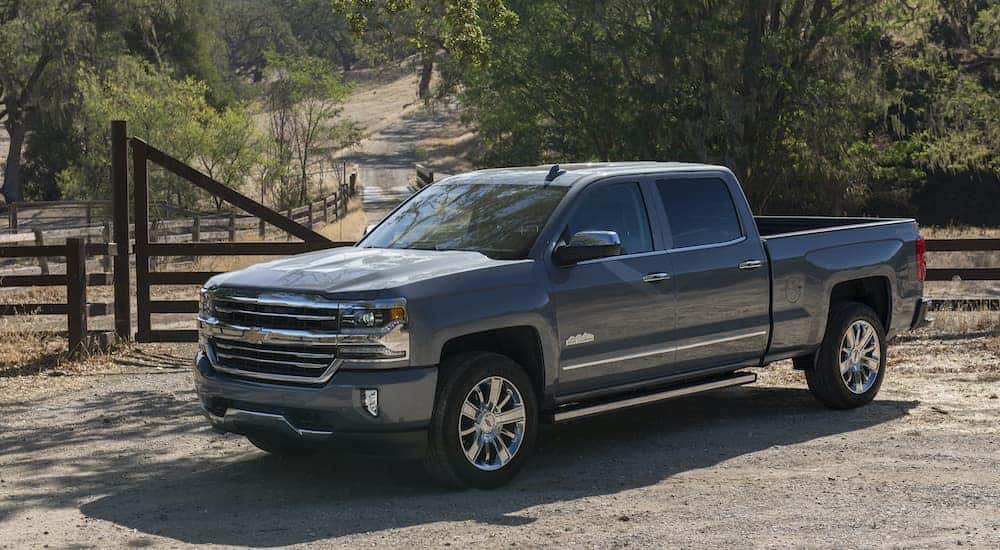A grey 2017 Chevy Silverado 1500 is shown from the side parked in front of a fence.