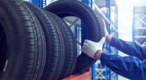 A mechanic is shown pulling a tire down from a tire rack.