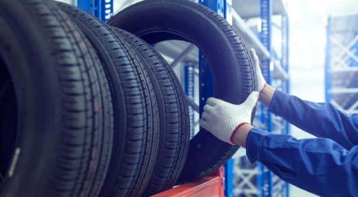 A mechanic is shown pulling a tire down from a tire rack.