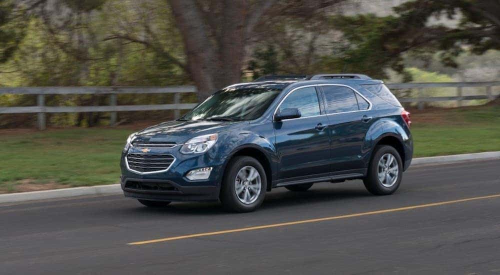 A blue 2016 Chevy Equinox is shown from the front at an angle while driving down the road.