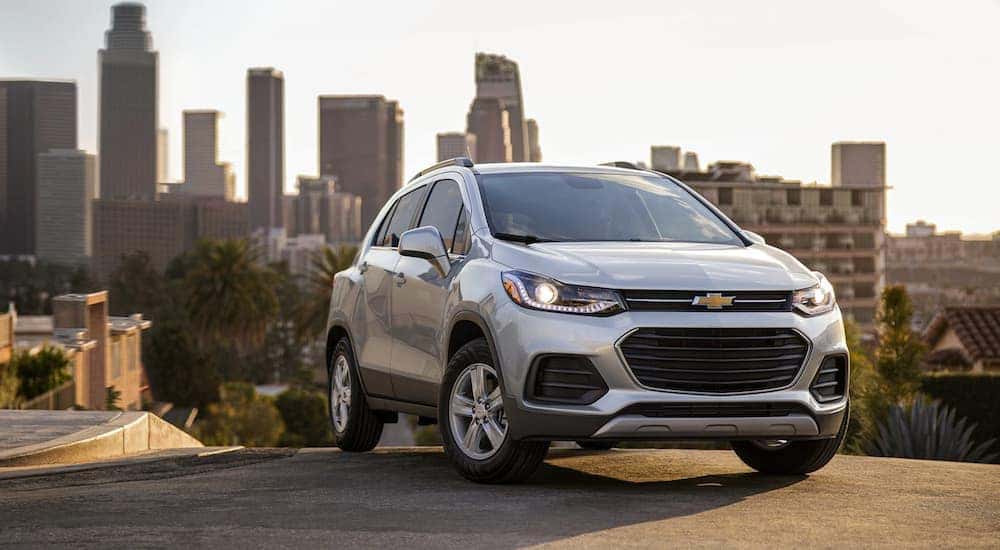 A silver 2022 Chevy Trax is shown from the front at an angle parked in front of a city skyline after the owner searched 'Chevy dealers in OH'.