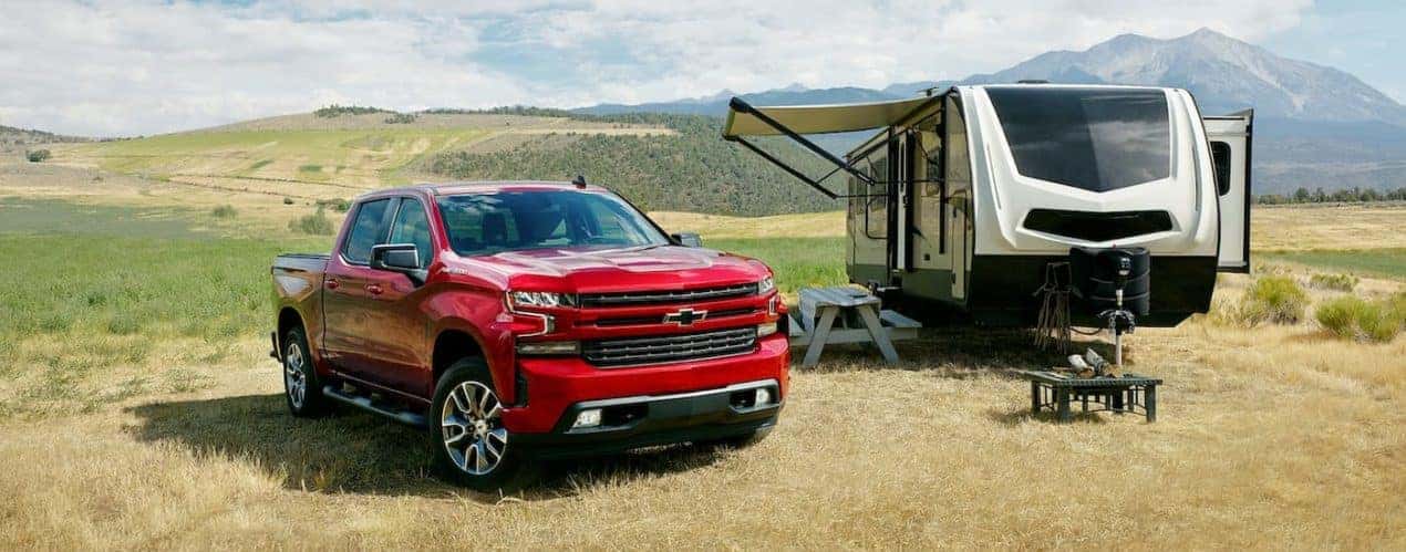 A red 2022 Chevy Silverado RST LTD is shown parked next to a camper.
