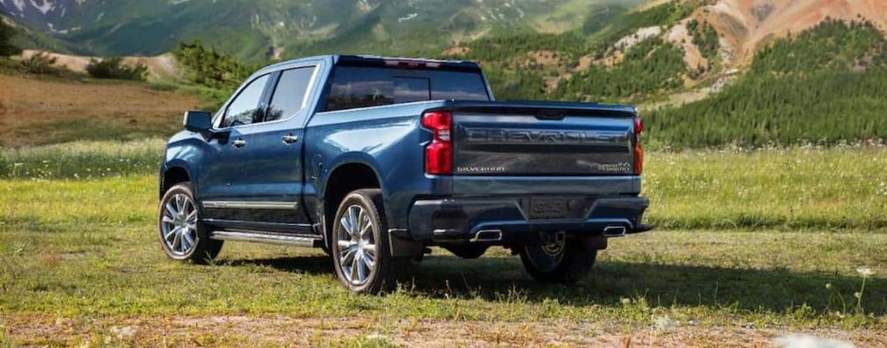 A blue 2022 Chevy Silverado 1500 High Country is shown parked in an open grassy field.