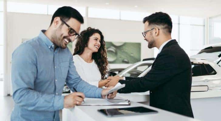A couple is shown talking to a salesperson and filling out information on a clipboard at a Chevy dealer in OH.