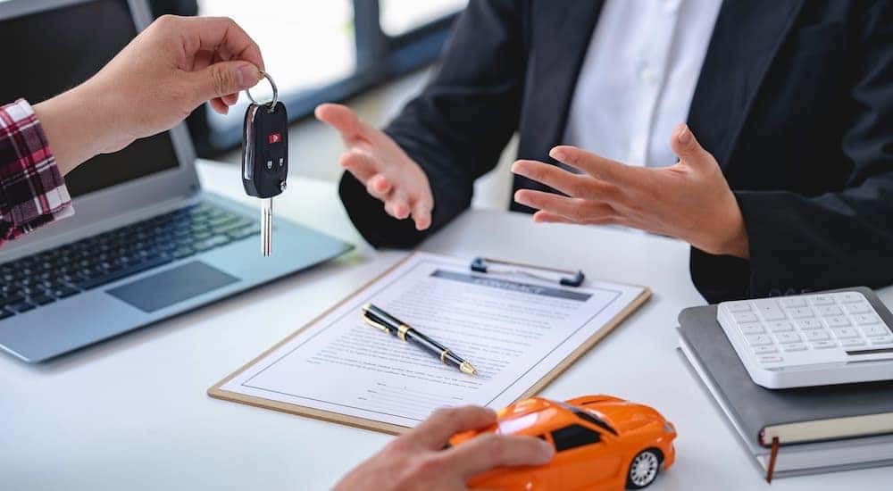 A person is shown talking to a salesperson over paperwork.