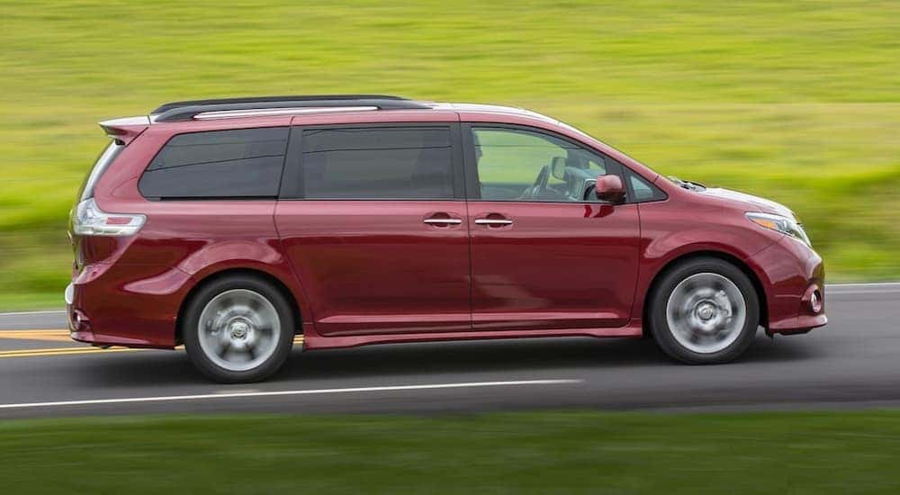 A red 2018 Toyota Sienna is shown from the side driving on an open road.