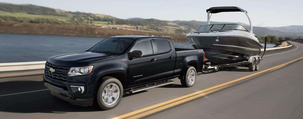 A black 2022 Chevy Colorado is shown from the side towing a boat.