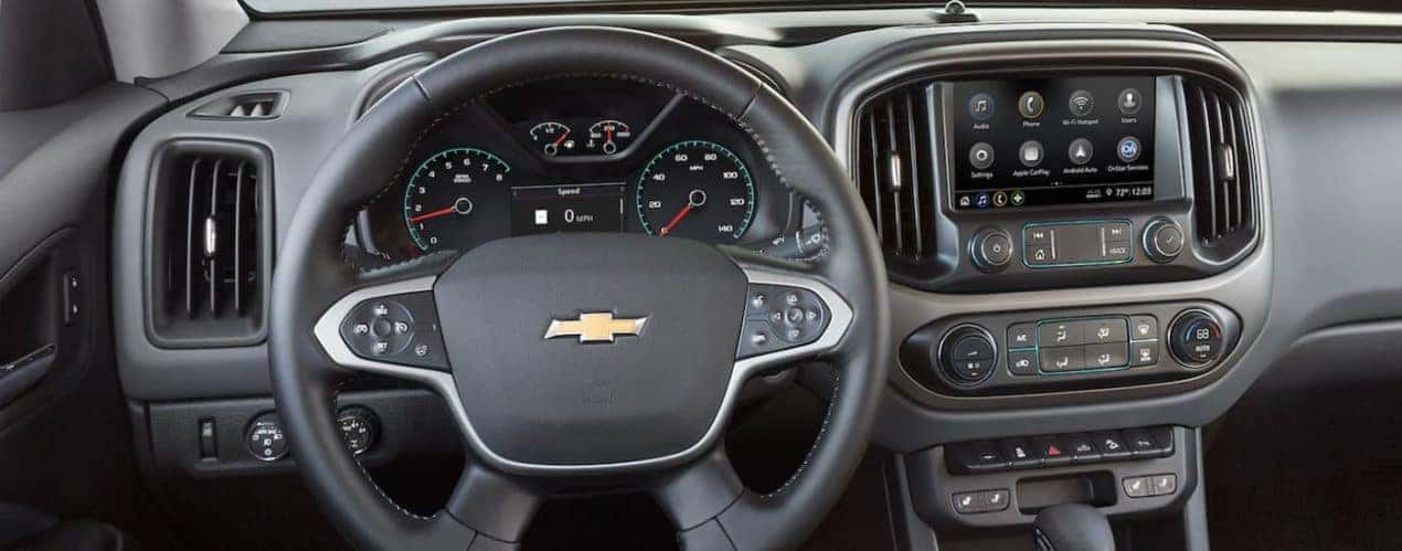 The black interior of a 2022 Chevy Colorado shows the steering wheel and infotainment screen.