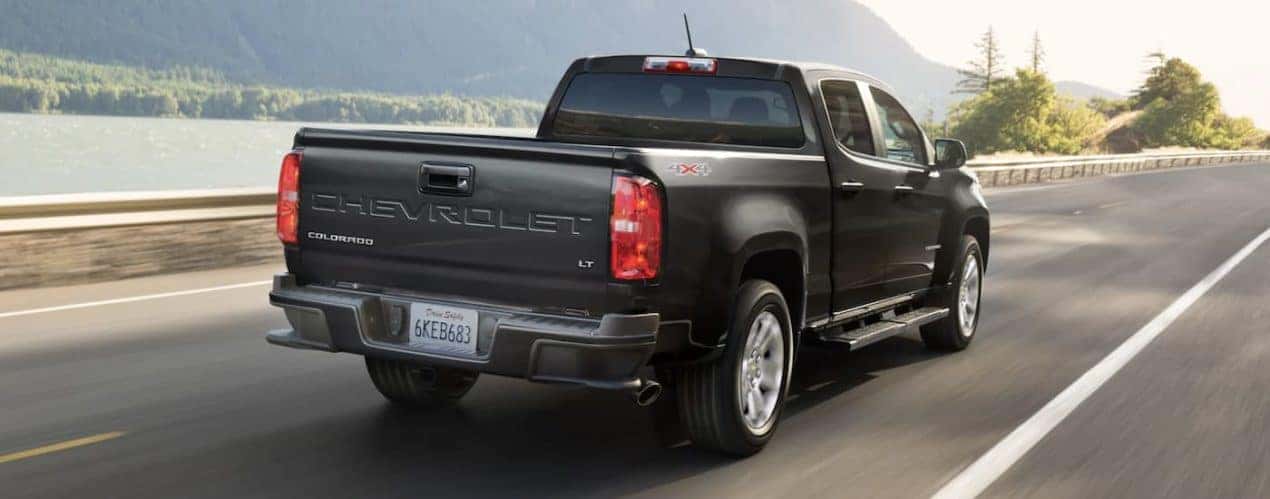 A black 2022 Chevy Colorado is shown from the rear driving on an open road during a 2022 Chevy Colorado vs 2022 Toyota Tacoma comparison.