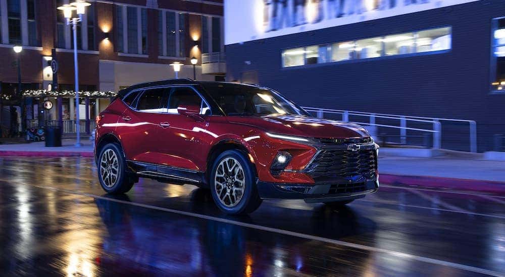 A red 2023 Chevy Blazer RS is shown from the front at an angle on a city street at night.