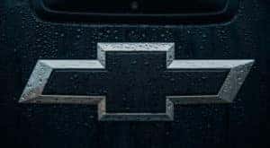 A black Chevy logo is shown covered in dew drops.