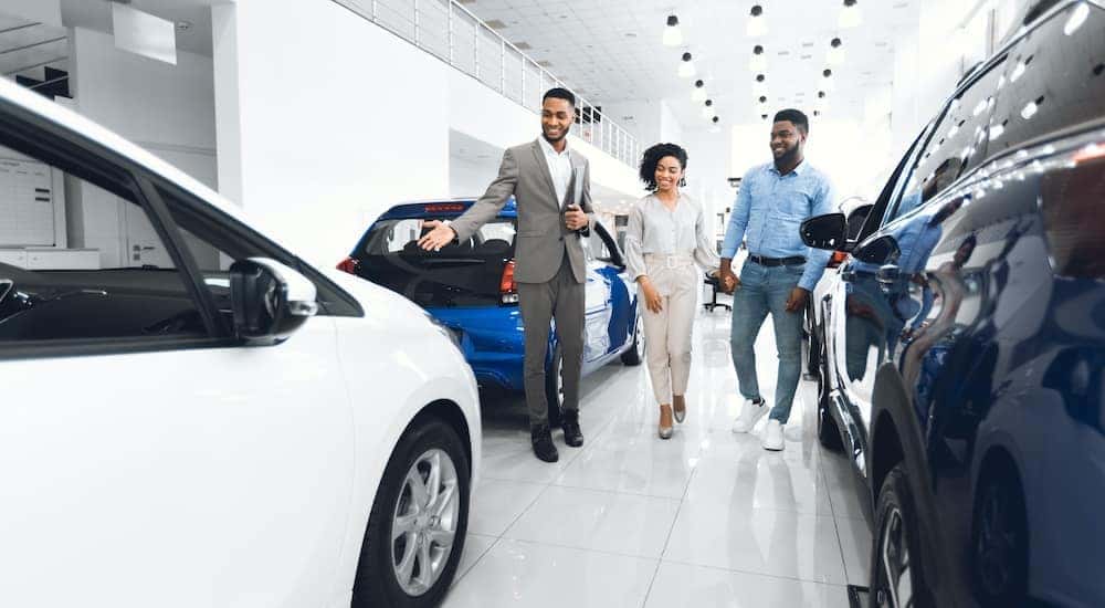 A man is walking a couple trough a car dealership.