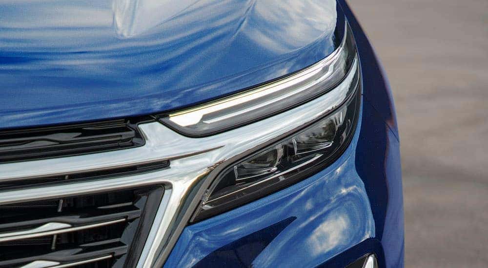 A close up shows the driver side headlight on a blue 2022 Chevy Equinox Premier.
