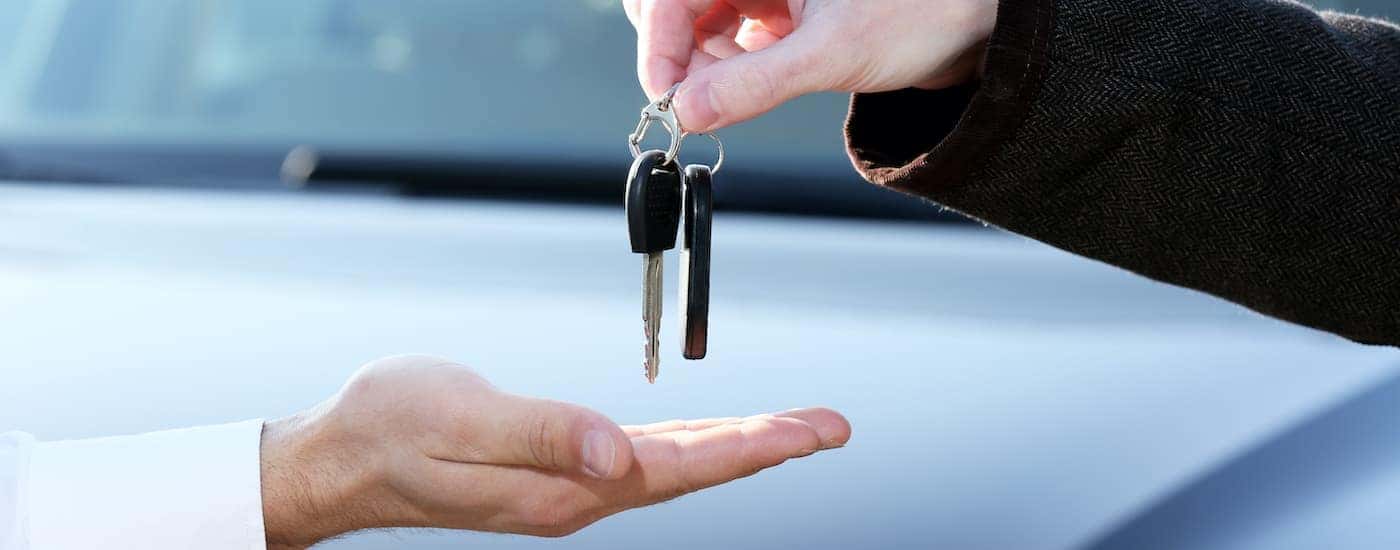 A hand is shown passing a set of car keys.