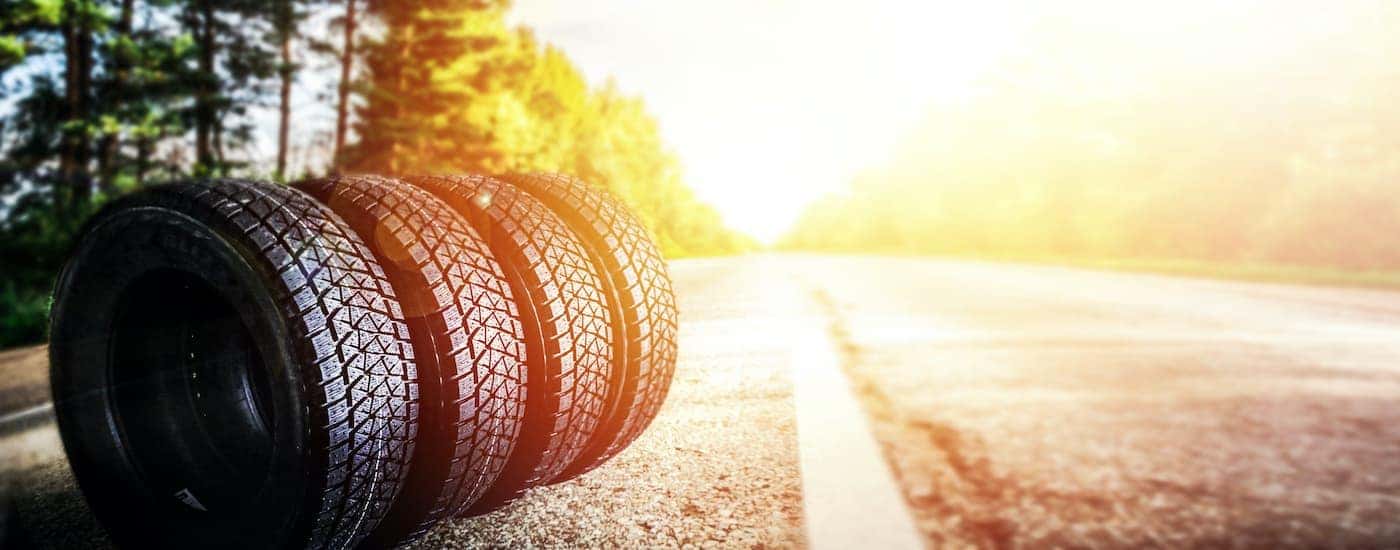 Four tires are shown in a row to the side of a road.