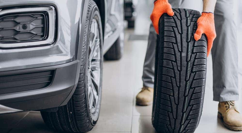 A mechanic is shown rolling a tire at an all season tire dealer.