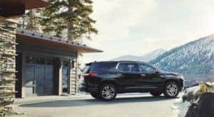A black 2018 Chevy Traverse is shown from the side parked next to a garage.