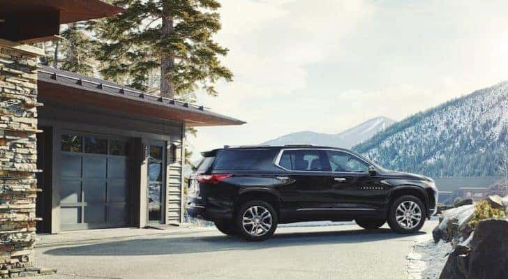 A black 2018 Chevy Traverse is shown from the side parked next to a garage.