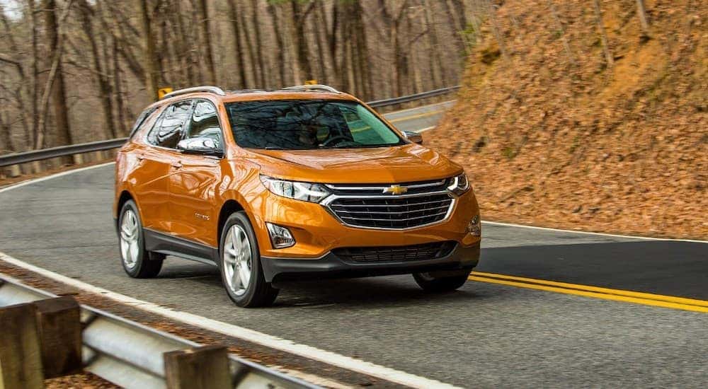 An orange 2018 Chevy Equinox is shown from the front at an angle after leaving a dealership that advertised having a used Chevy Equinox.