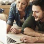 A couple is shown searching, 'How Does Buy Here Pay Here Work', on their laptop.
