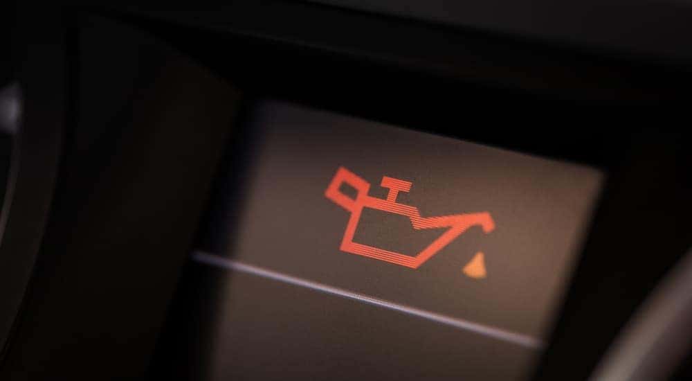 An oil change light on a car dashboard is shown lit up.