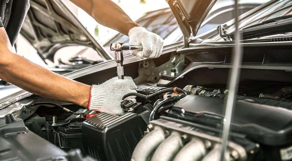 A close up of a mechanic working on a vehicle's engine is shown.