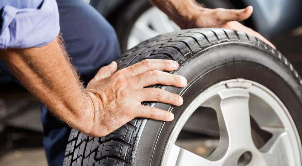 A person is shown moving a tire and rim after deciding to sell their car fast.