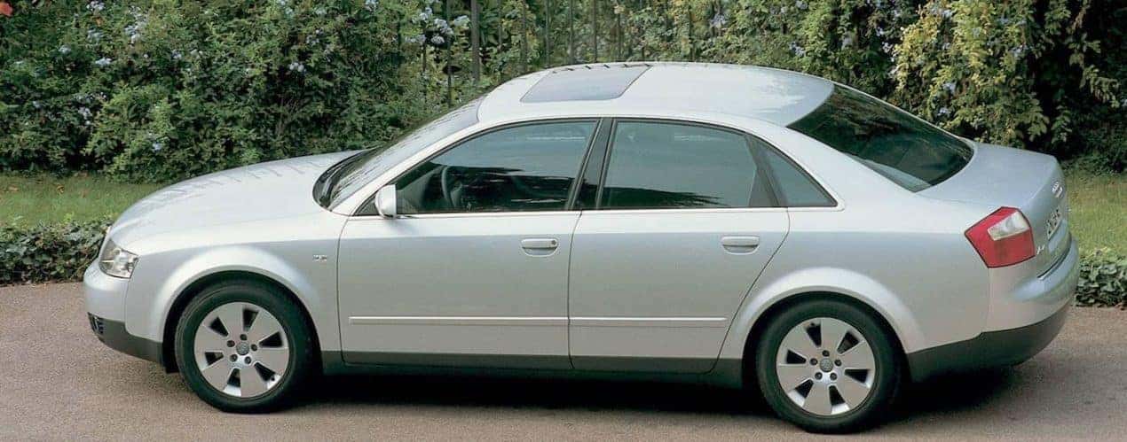A silver 2000 used Audi A4 is shown next to bushes.