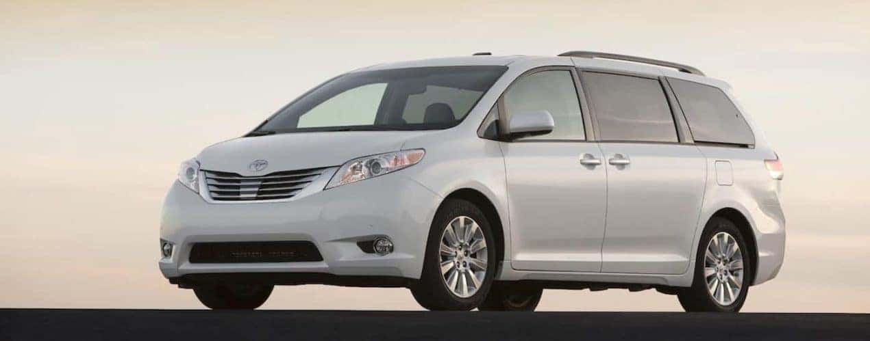 A grey 2010 used Toyota Sienna is shown parked in front of a skyline.
