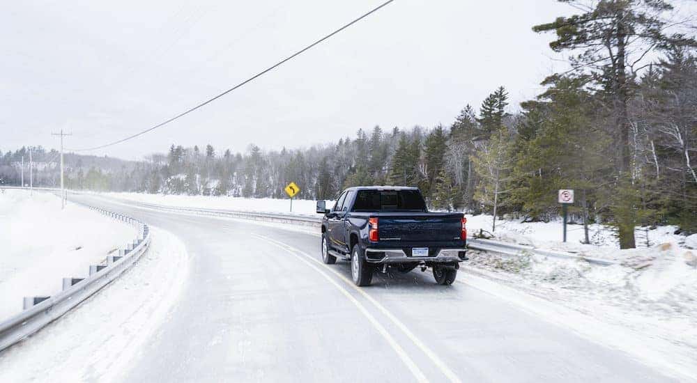 A blue 2020 Chevy Silverado 2500HD is shown from the rear on a snowy road after getting winter tires in Cincinnati.