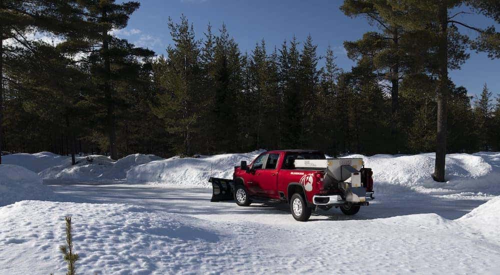 A red 2020 Chevy Silverado 3500HD is shown from the rear at an angle while equipped with a plow and a sander.