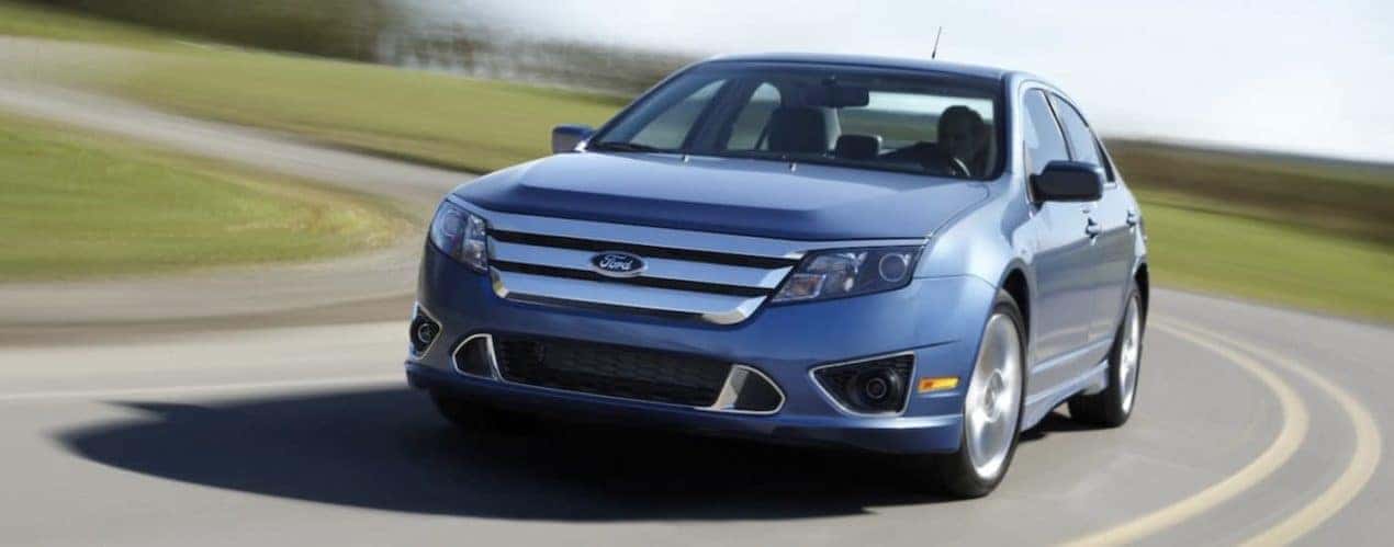 A blue 2010 Ford Fusion is shown driving on an open road.