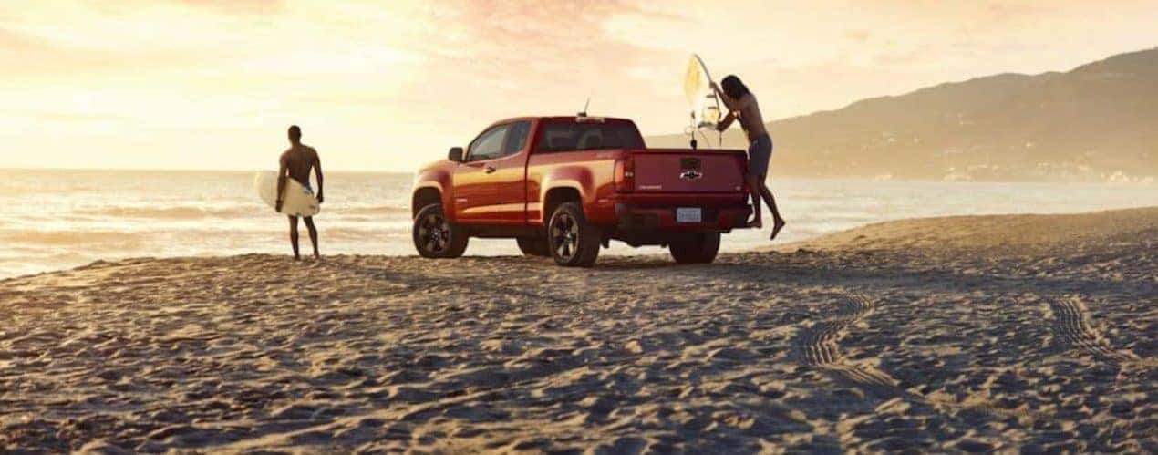 An orange 2016 Chevy Colorado is shown from the rear at an angle on the beach.