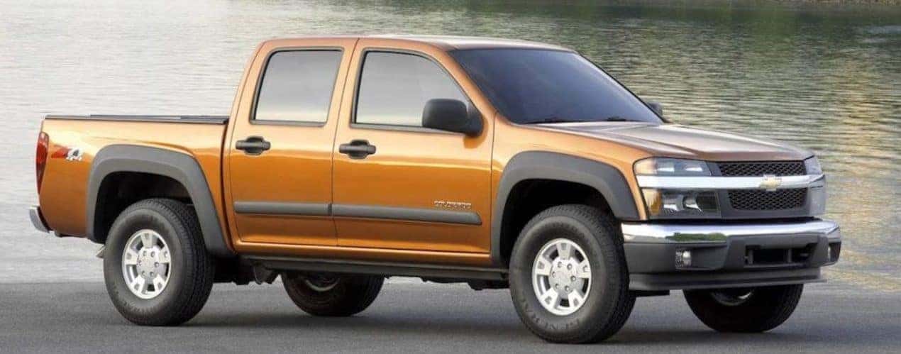 An orange 2007 Chevy Colorado is shown from the front at an angle after leaving a dealer that had a used Chevy Colorado.