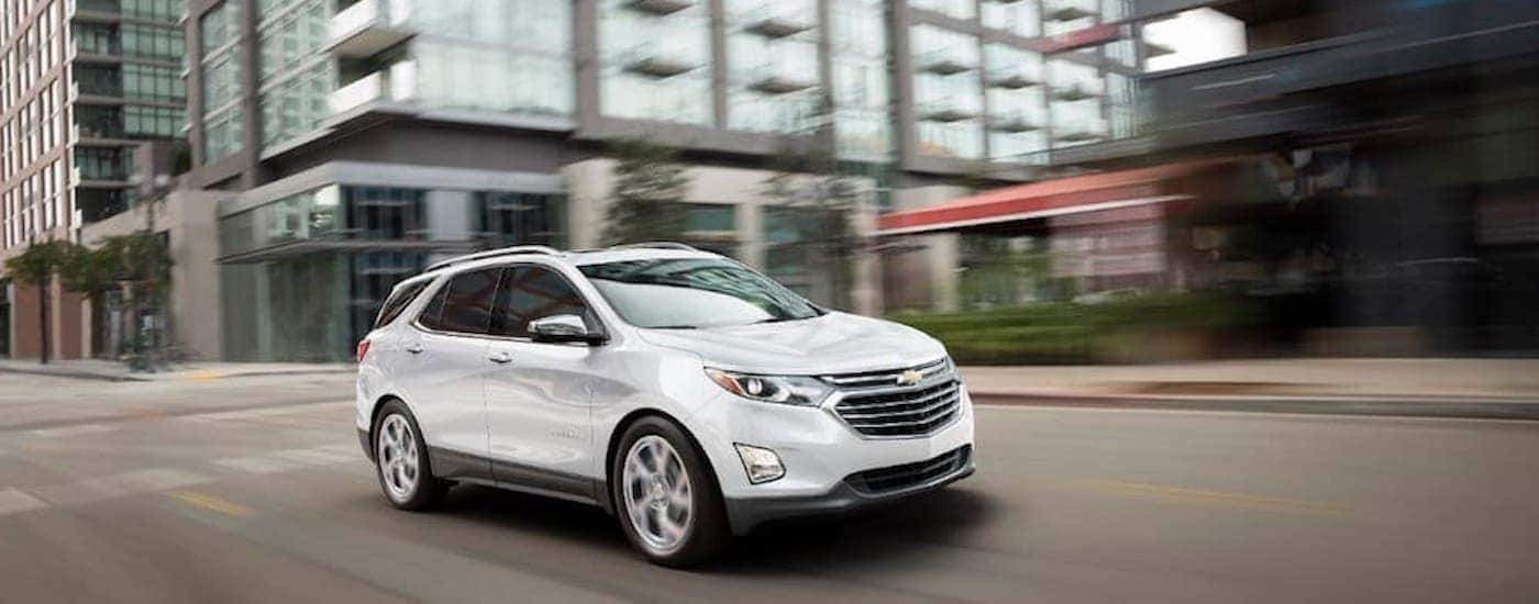 A white 2018 Chevy Equinox is shown from the front at an angle while driving through a city.