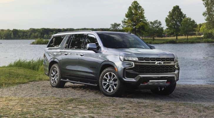 A silver 2021 Chevy Suburban Z71 is shown from the front at an angle while parked on a lakeside after leaving a used SUV dealer.