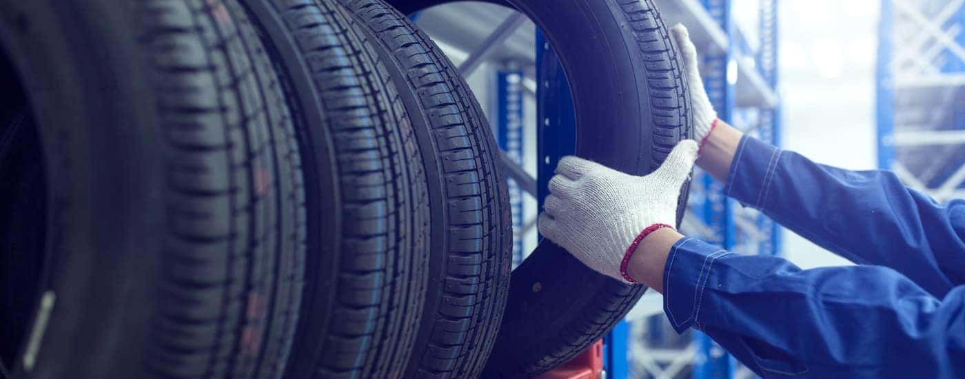 A mechanic is shown pulling a tired from a rack.