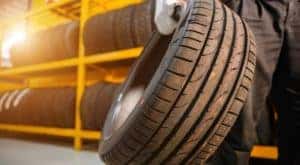 A mechanic is shown carrying a tire at a tire store in Hamilton OH.