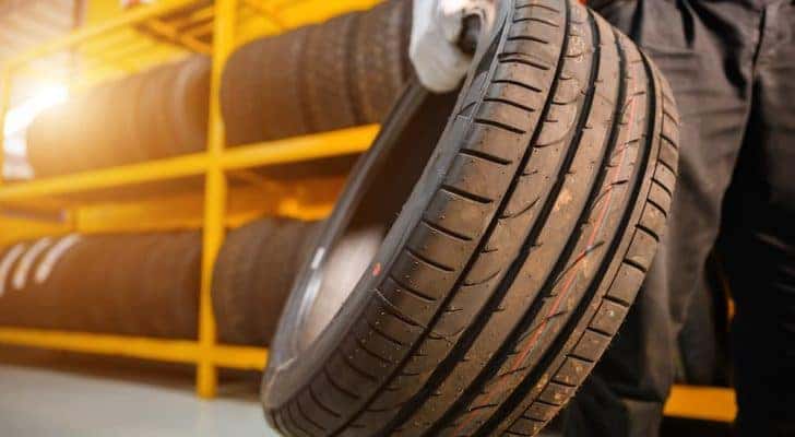 A mechanic is shown carrying a tire at a tire store in Hamilton OH.