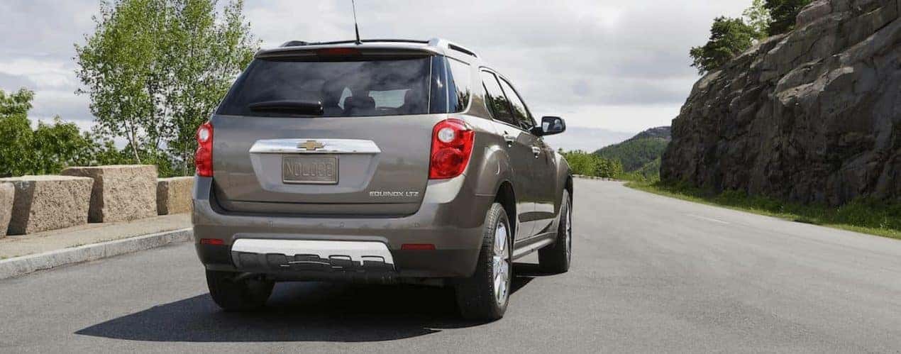 A beige 2013 used Chevy Equinox is driving up a rock lined road. Check one out a Cincinnati, OH dealership.