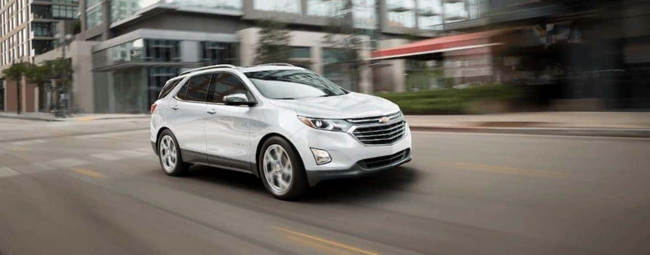 A white 2019 used Chevy Equinox is driving downtown in Cincinnati, OH.