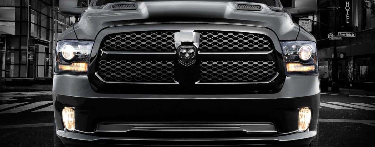 The front of a black 2012 Ram 1500 is shown at night.